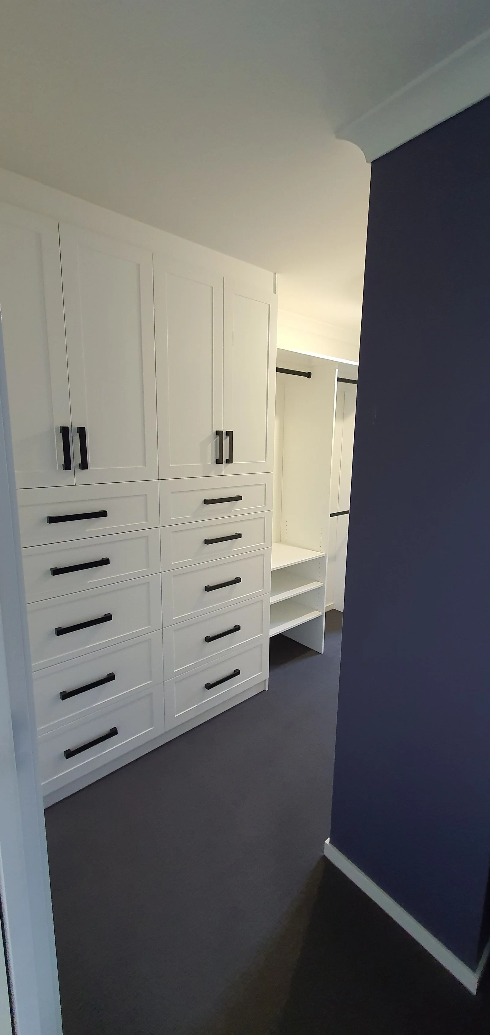 Built-in wardrobe with white hinged doors and brushed handles