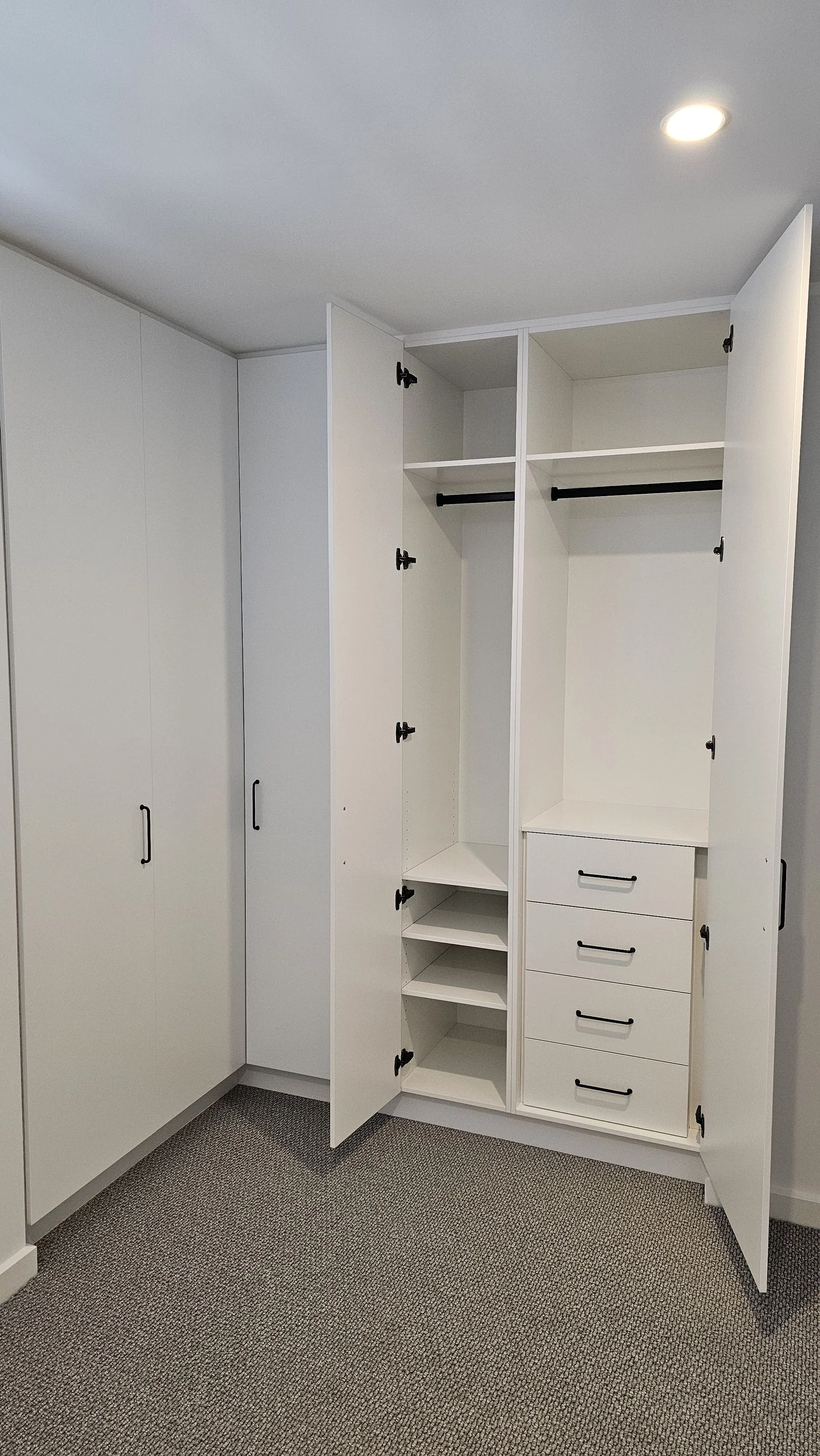 Floor-to-ceiling wardrobe cabinetry fitted by Brodco in a large bedroom
