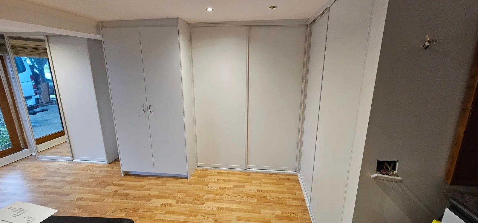Built-in wardrobe with mirrored sliding doors and side cabinetry