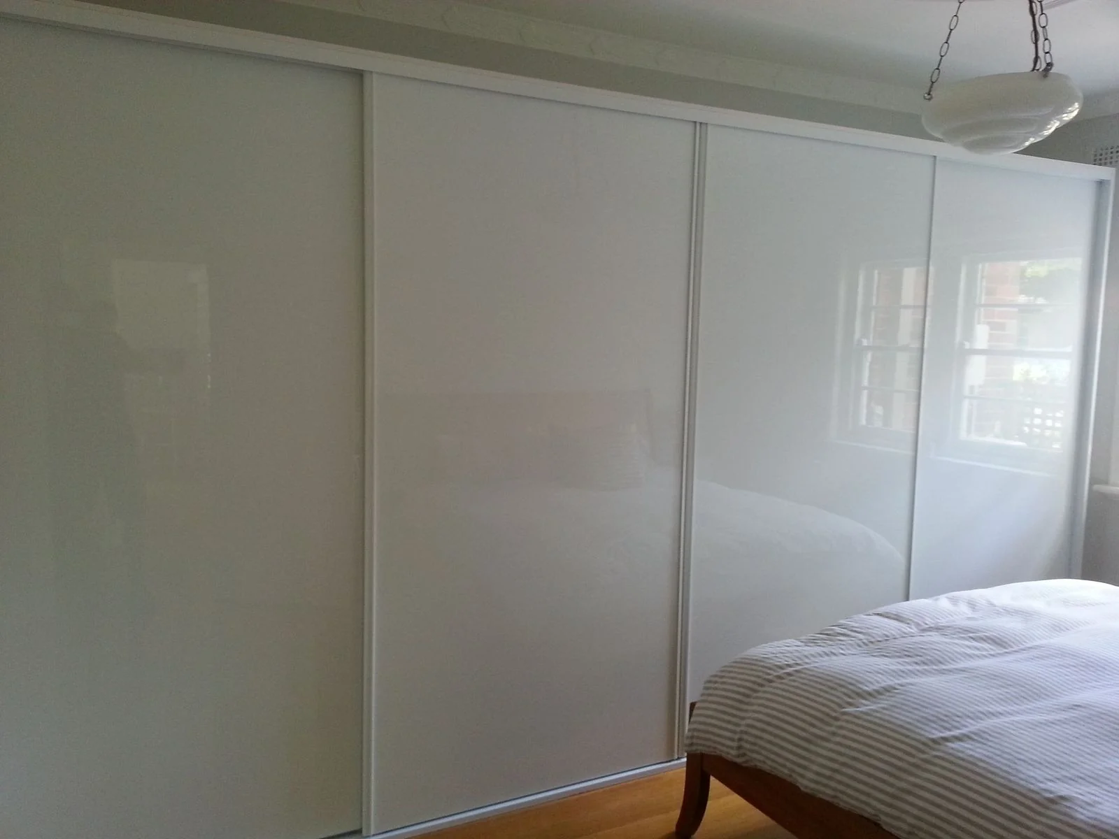Built-in wardrobe with white sliding doors in a bright bedroom