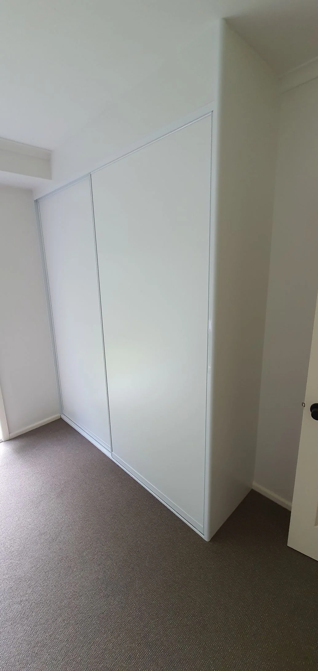 Built-in wardrobe with mirrored sliding doors and side cabinetry