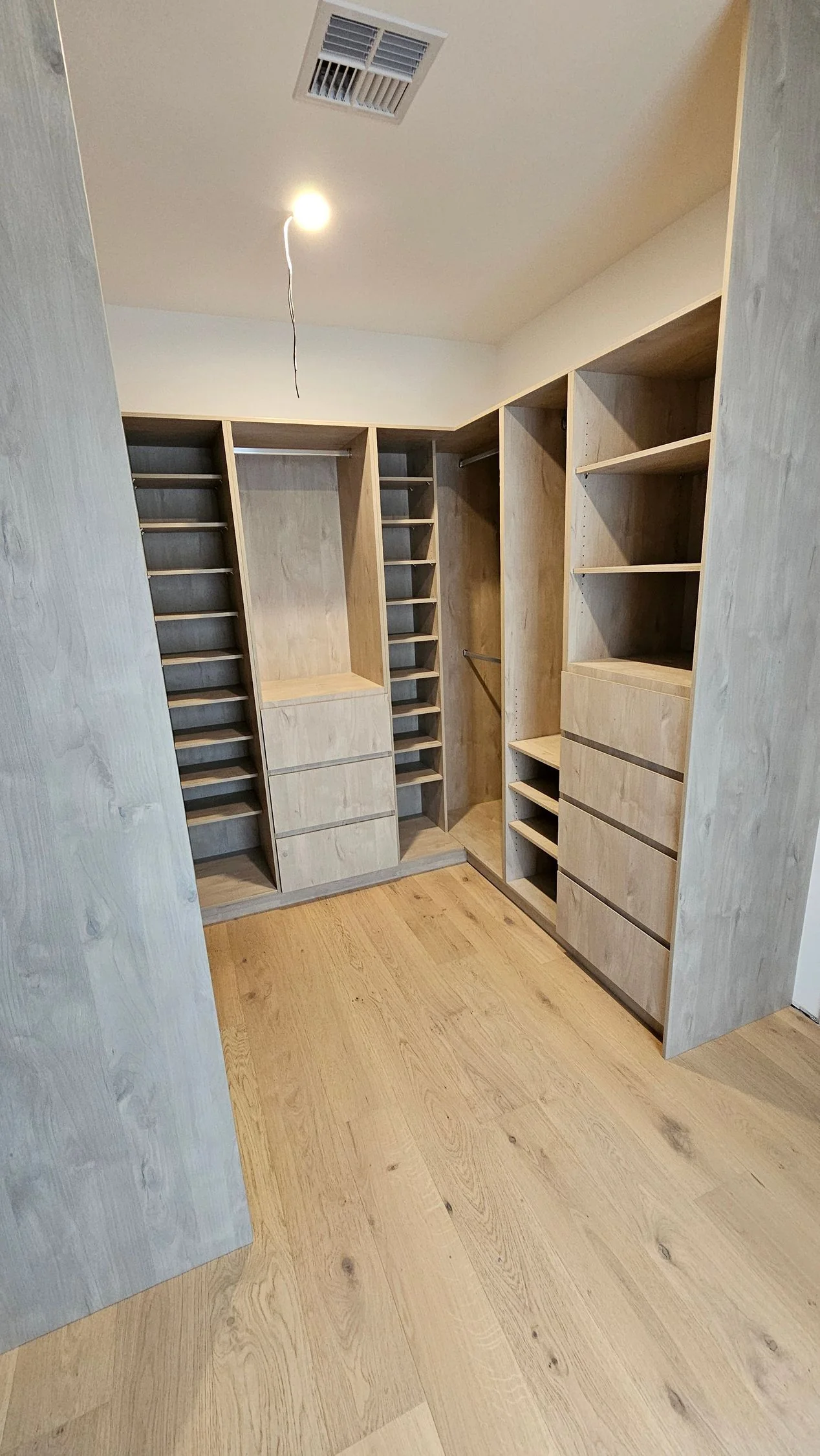 Walk-in wardrobe with timber shelving and a hanging bay